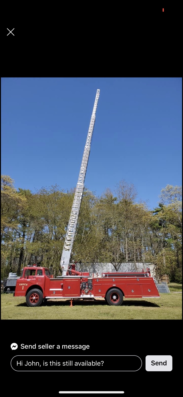 Screenshot of an online marketplace listing showing a red vintage ladder fire truck marked Truck 1 parked on grass with its aerial ladder fully raised against a blue sky.
